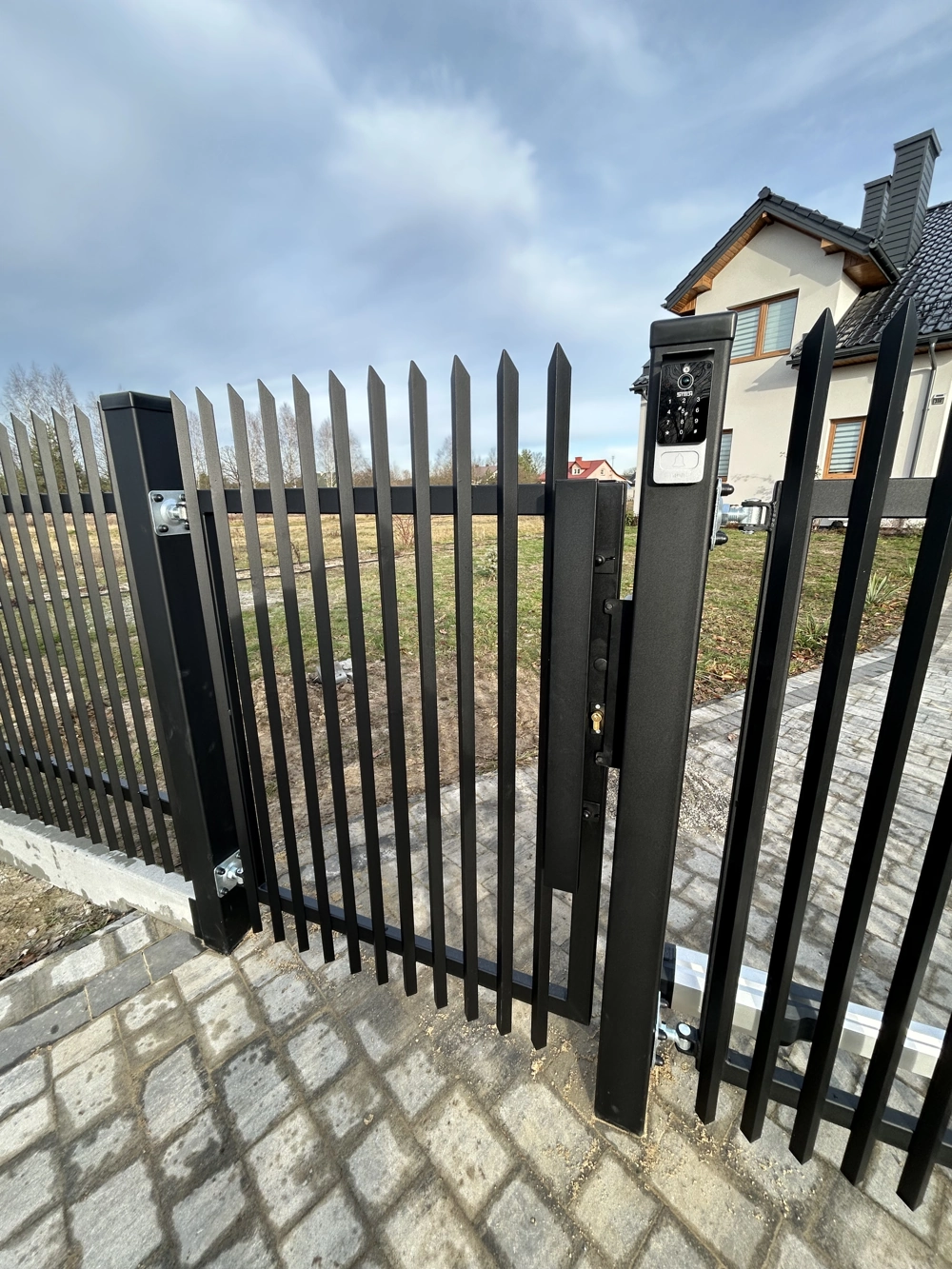 Furtka z ogrodzenia palisadowego z domofonem na słupku multimedialnym